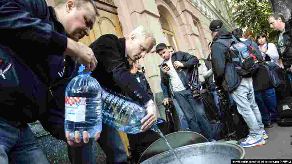 Віталій Шабунін – голова правління Центру протидії корупції (в центрі) наливає воду у символічну юшку біля комітетів Верховної Ради під час акції «Депутати, ви уху їли?»