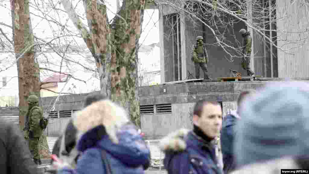 А у Верховной Рады Крыма рядом с четырьмя пулеметами Калашникова переминались с ноги на ногу четыре пулеметчика. На высоких мраморных парапетах бассейнов перед зданием были положены два деревянных поддона, первоначально притащенных активистами от ближайшего супермаркета для строительства баррикад. На этих паллетах и стояли пулеметы, по два на каждом. Коробки с патронами были пристегнуты к пулеметам, ленты заправлены в приемники. Несколько спецназовцев стояли перед парапетами, а перед ними, в свою очередь, густой цепью расположились «ополченцы». Подойти ближе, чтобы  сделать фотографию, активисты не позволили.