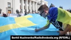 Люди написали побажання на великому кримськотатарською прапорі, який запустять в Крим до Дня кримськотатарського прапора. Київ, 15 червня, 2021 року