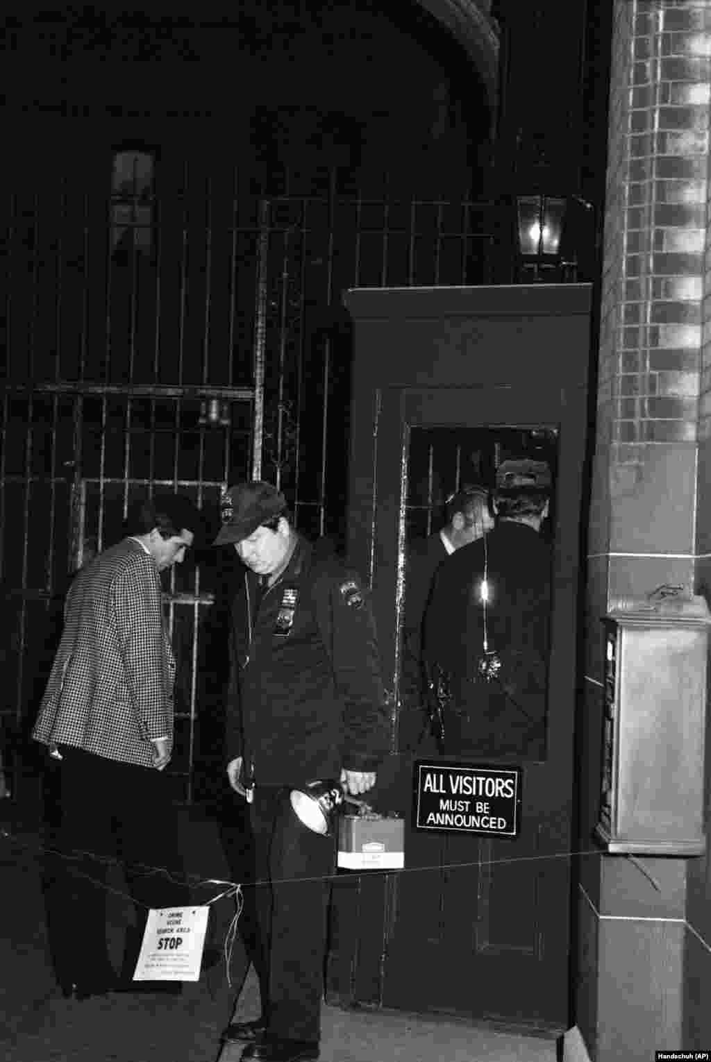 Полиция осматривает вход в многоквартирный дом «Дакота» в Нью-Йорке, 8 декабря 1980 года. Джон Леннон, живший в этом здании, был убит возле входа, возвращаясь домой. В стеклянных дверях видны следы от пуль