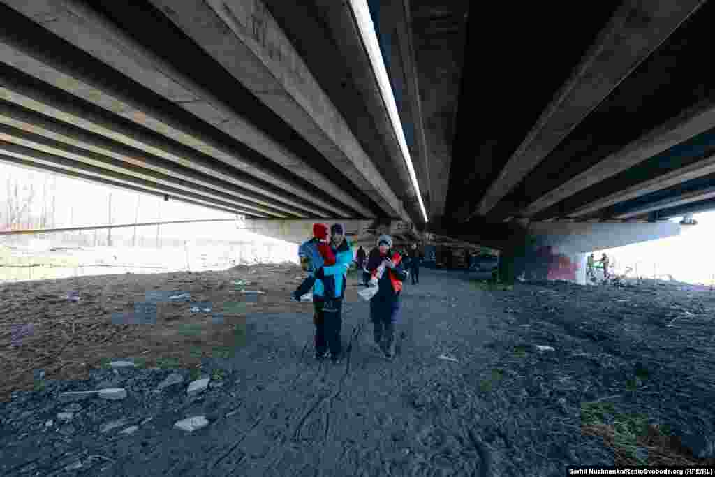 Родина з дітьми переховується від обстрілу під естакадою підірваного Романівського мосту.Ліворуч фото від 11 березня 2022, праворуч – березень 2025 року