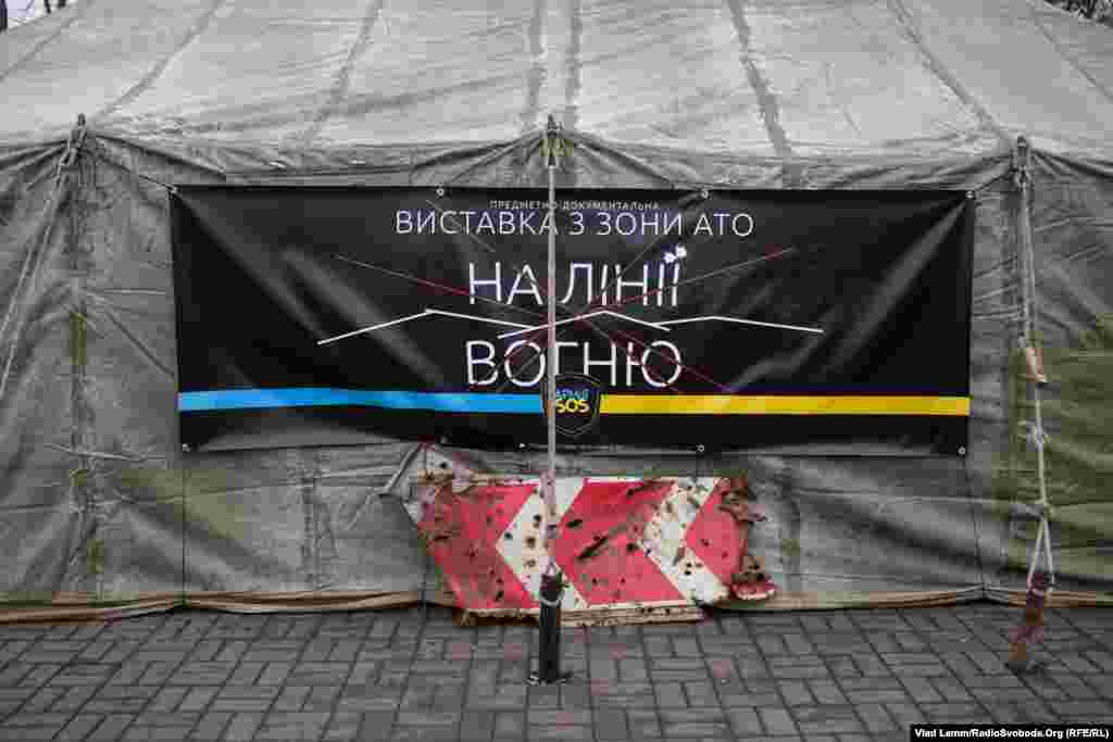 Банер волонтерської організації «Армія SOS» поряд з дорожнім знаком, привезеним з Донбасу