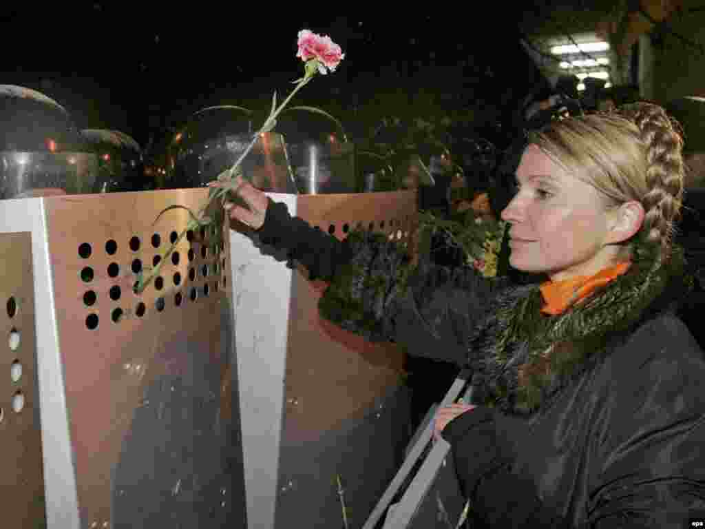 Юлія Тимошенко чіпляє гвоздики на щити ОМОНу біля адміністрації президента після так званого «штурму Банкової» під час Помаранчевої революції. Київ, 23 листопада 2004 року