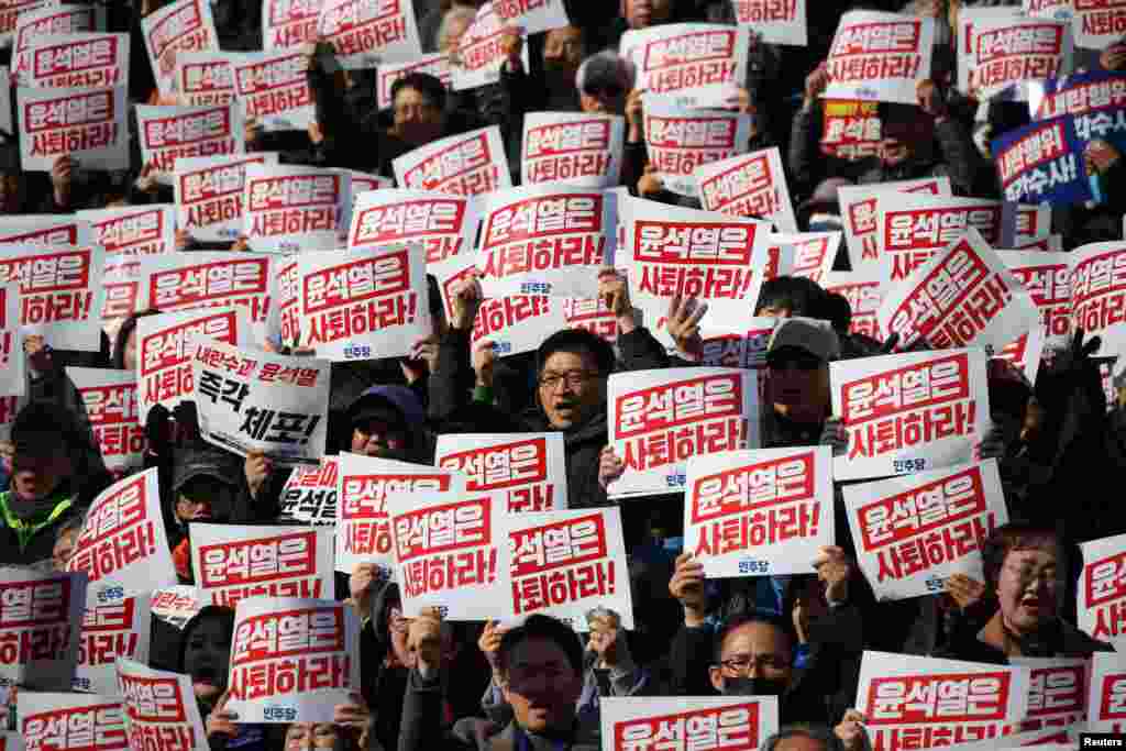 Протестующие держат плакаты с надписью "Уйдите с поста президента Юн Сук Ёля". Люди, участвующие в митинге, осуждающем неожиданное объявление президентом Южной Кореи военного положения, призывают к его отставке, Национальное собрании в Сеуле, Южная Корея, 4 декабря 2024 года. 