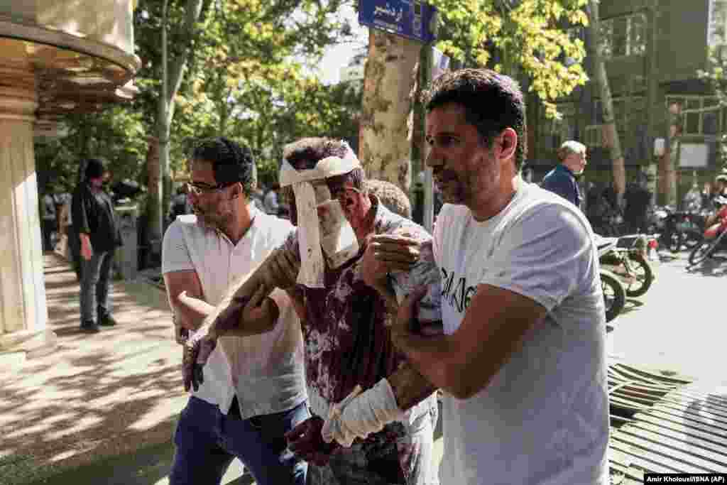 Пораненого чоловіка відводять від місця вибуху в центрі Тегерану 15 червня 2025 року