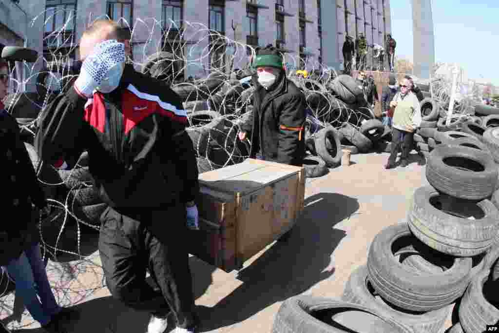 Проросійські активісти, які захопили будівлю Донецької ОДА, несуть ящик маркований, як протигази ГП-5М. Сепаратисти оголосили «незалежність Донецької республіки». Донецьк, 7 квітня 2014 року