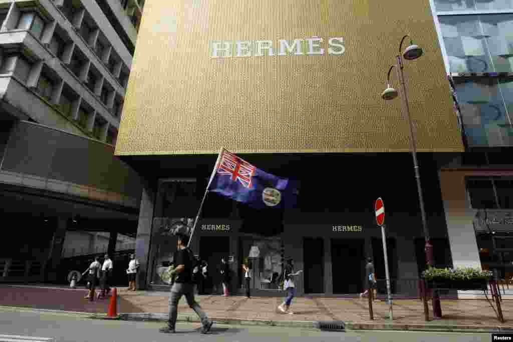 Протестующий с флагом Гонконга времен его колониального подчинения Великобритании