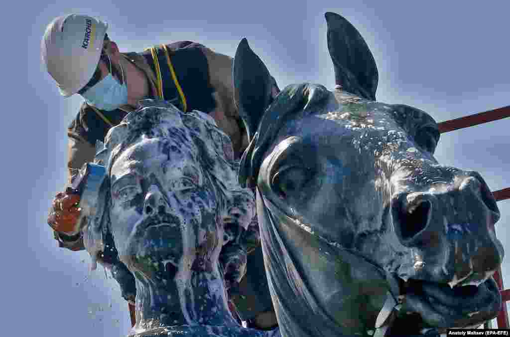 Муніципальний робітник на підйомному крані очищає пам'ятник царю Петру І під час підготовки до Дня міста в Санкт-Петербурзі 26 травня (epa-EFE/Anatoly Maltsev)