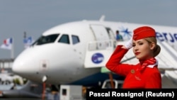A cabin crew member of Russian carrier Aeroflot poses in front of a Sukhoi Superjet 100. Cracks are showing in Russian aviation industry as it struggles under the weight of Western sanctions that have sharply curtailed the import of badly needed parts. (file photo)