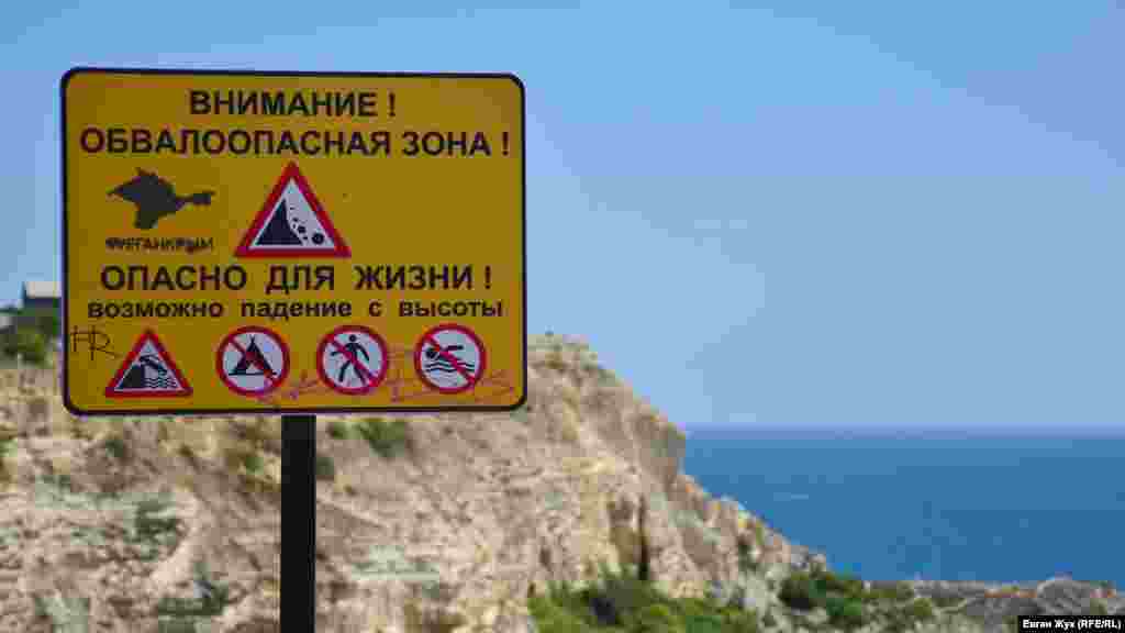 Табличка предупреждает об опасности свалиться вниз – высота обрыва здесь от 50 до 60 метров