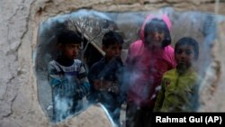 Internally displaced boys are reflected in a mirror inside their temporary home in the city of Kabul on December 30.
