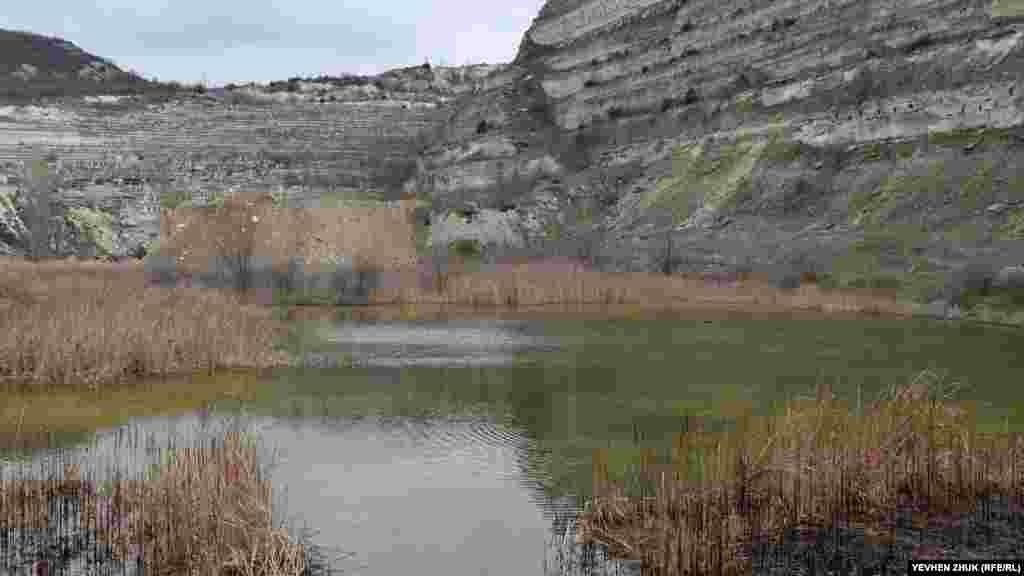 «Обратная сторона» Загайтанской скалы – карьер, огромный котлован с вертикальными выпиленными стенами высотой до 50 метров. На дне карьера образовалось небольшое озеро с водой желтоватого цвета