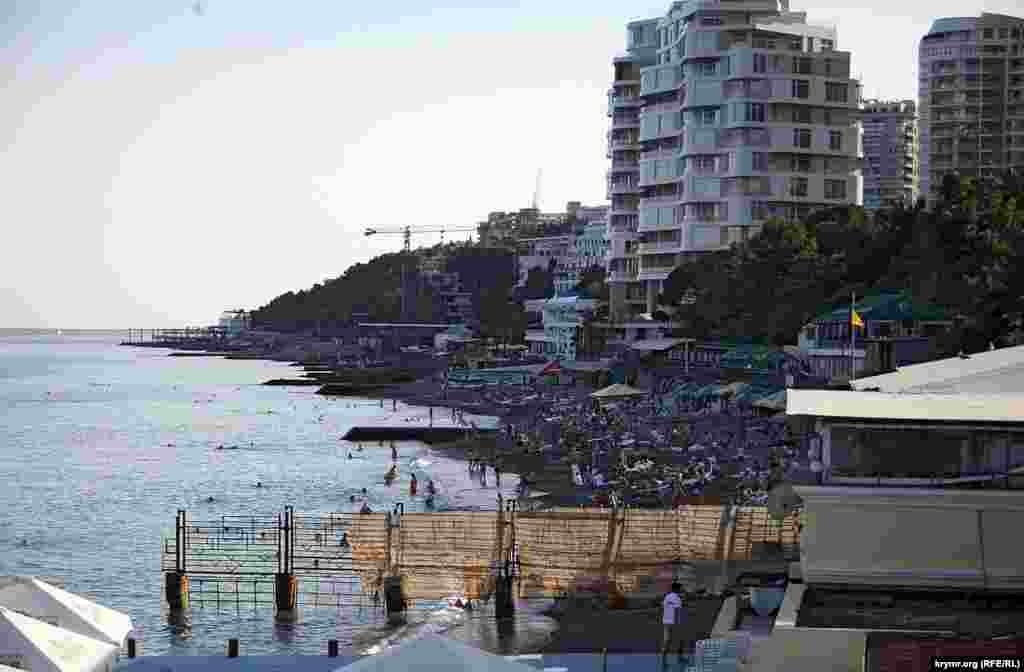 Городской пляж в Приморском парке, напротив легендарной гостиницы «Ореанда». Люди есть, так что днем это пляж, очевидно, заполнен. Правда,  городским является только  ближняя часть пляжа, следующие карты пляжей расхватали новоявленные застройщики, а дальше начинаются владения курортного монстра – санатория «Россия», бывшей собственности ЦК КПСС. Ржавым забором с накинутой на него рваной маскировочной сеткой ограждает свой пляж от городского  дирекция гостиницы «Ореанда» (пляж гостиницы на фотографии  внизу)