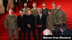 Боно, Едж та Шон Пенн разом із українськими військовослужбовцями на червоній доріжці 78-го Каннського кінофестивалю перед показом документального фільму «Боно: Історії капітуляції». Канни, Франція, 16 травня 2025 року