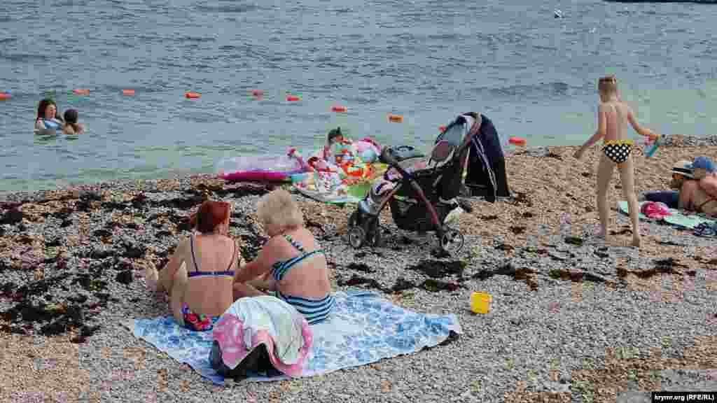 Родители с детьми загорают на берегу «лягушатника» – мелководного участка пляжа для детей