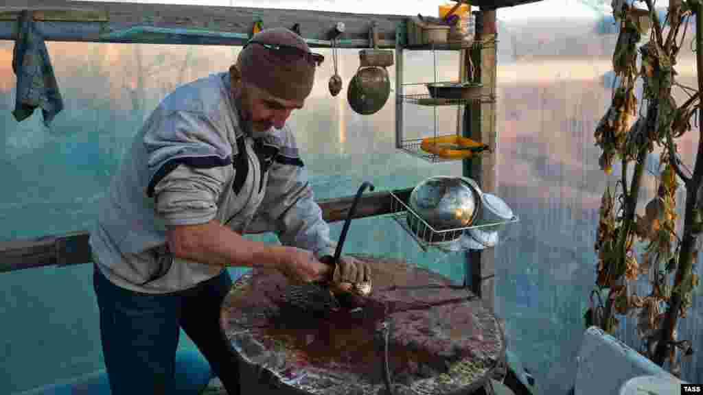 Мастер по изготовлению медных изделий Рефат Куртвелиев за работой в своей мастерской в селе Почтовом