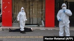 Медработники в защитных костюмах эвакуируют умершего на улице в Ухане рядом с одной из местных больниц, 30 января 2020 года