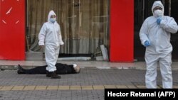 Медработники в защитных костюмах эвакуируют умершего на улице в Ухане рядом с одной из местных больниц, 30 января 2020 года