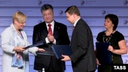 Віце-президент Єврокомісії Валдіс Домбровскіс, президент України Петро Порошенко, голова НБУ Валерія Гонтарєва та міністр фінансів Наталя Яресько підписують угоду про макрофінансову допомогу на саміті «Східного партнерства» у Ризі, 22 травня 2015 року