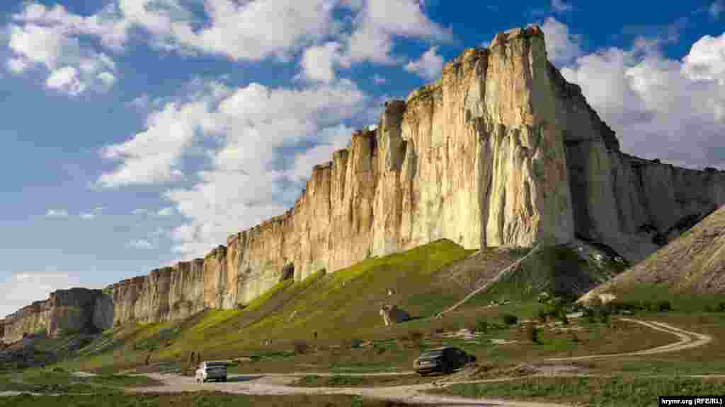Ак-Кая особо красочно смотрится ближе к вечеру, когда солнце освещает ей «в анфас». В центре виднеется Большой грот
