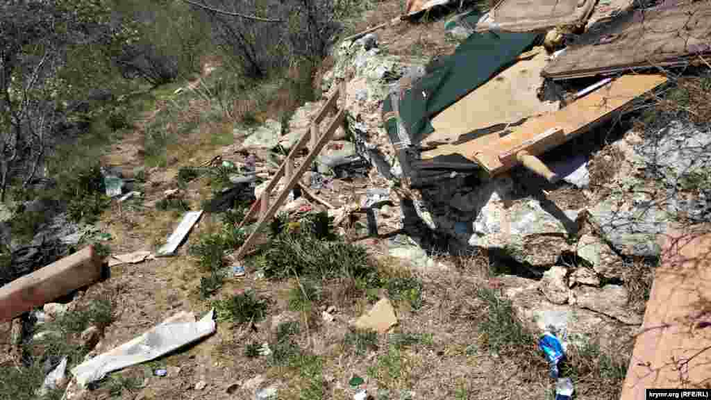 Ниже многоквартирных домов на склоне – горы бытового мусора