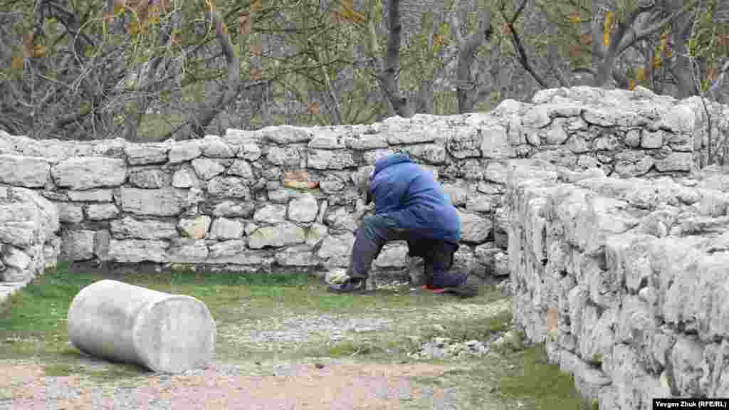 Работник обтесывает топором камни 