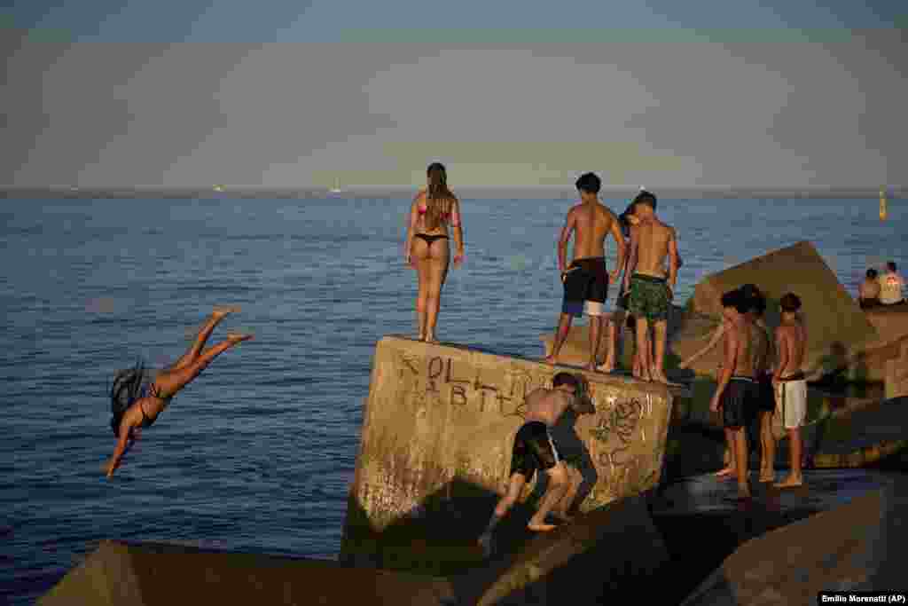 Mladi ljudi skaču u vodu sa litice pored mora, u Barseloni, Španija, 29. juna.