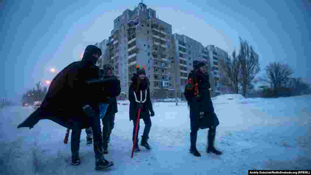Учасники різдвяного вертепу з авдіївського осередка скаутської організації «Пласт» йдуть колядувати у стару частину міста повз розбиті боями дев'ятиповерхівки на околиці Авдіївки, 7 січня 2019 року  