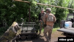 Ukrainian soldiers load ammunition and critical supplies onto a fibre-optic ground drone for frontline delivery.