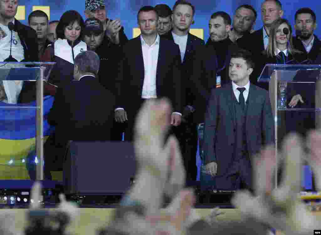 Кандидати в президенти Володимир Зеленський та Петро Порошенко стали на коліна на сцені НСК &laquo;Олімпійський&raquo; на знак пошани до родичів загиблих на Донбасі.&nbsp;Зеленський став на коліна, звертаючись до глядачів, а Порошенко опустився на коліно і поцілував державний прапор, який тримала волонтерка Тетяна Ричкова, чоловік якої загинув у 2014 році біля Єнакієвого. Київ, 21 квітня 2019 року