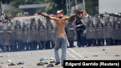 Після сутичок на кордоні Венесуели (позаду, за лавами венесуельської поліції) і Колумбії, з якої йде прихильник венесуельської опозиції, фото 23 лютого 2019 року